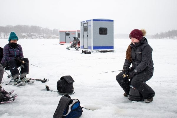 Woman Ice Fishing with Ambush Ice House In The Background