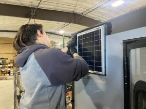 person installing solar panel in ambush skid house
