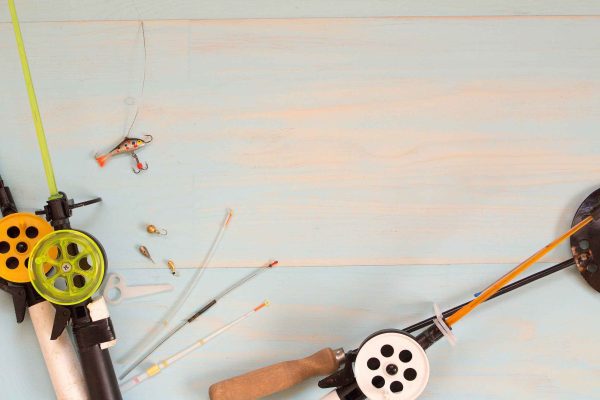 Tackle for winter fishing. Fishing rods and accessories on a wooden table. Top view