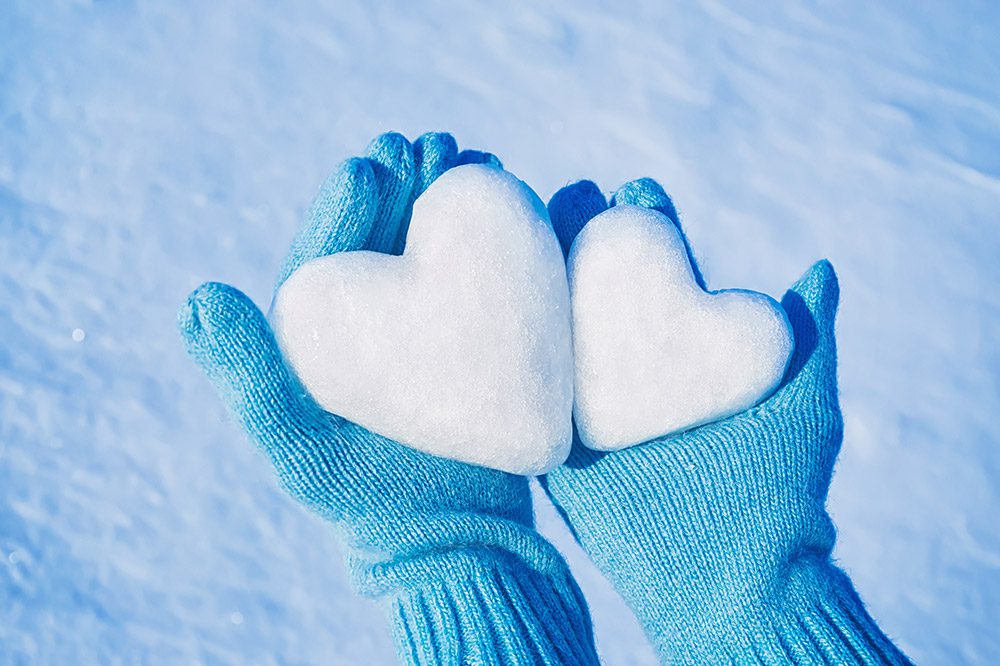 hands in knitted gloves with hearts of snow